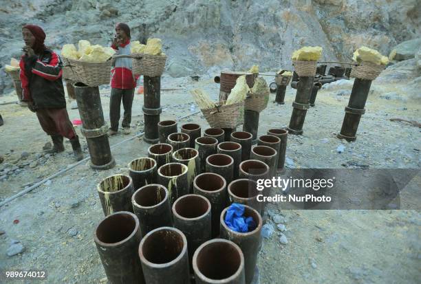 Residents of Mount Ijen take sulfur with a background of blue fire and hot steam at Ijen Crater, Banyuwangi, East Java, in July, 2.2018. Every day...