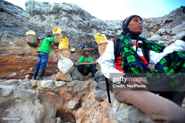 Residents of Mount Ijen take sulfur with a background of blue fire and hot steam at Ijen Crater, Banyuwangi, East Java, in July, 2.2018. Every day...