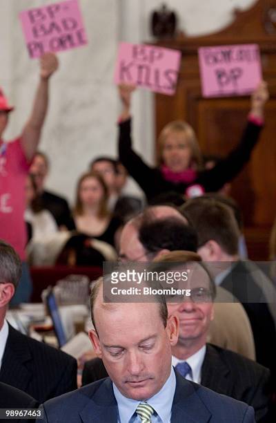 Protestors hold signs behind Lamar McKay, president and chairman of BP America Inc., during a Senate Energy and Natural Resources Committee hearing...
