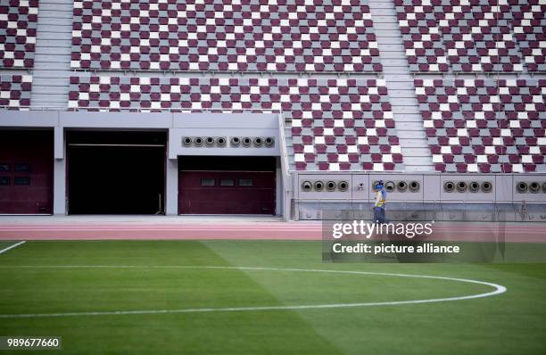 Workers walk on the court side in the Khalifa International Stadium in Doha, Qatar, 4 January 2018. The final round of the Soccer World Cup will be...
