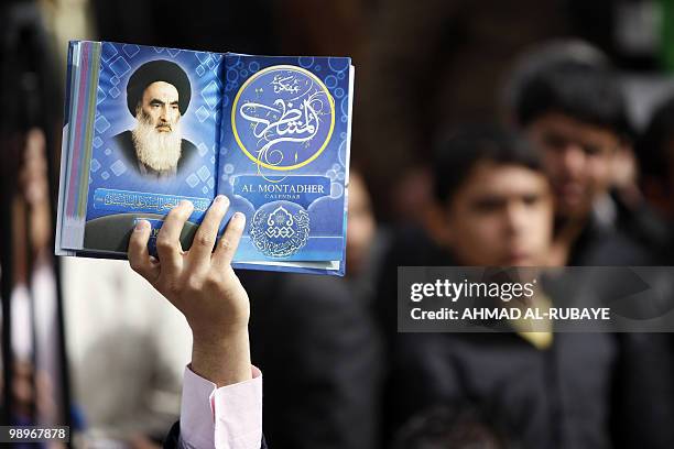 An Iraqi man holds a picture of top Shiite cleric Grand Ayatollah Ali Husseini al-Sistani at a campaign rally for Ammar al-Hakim, head of the Supreme...