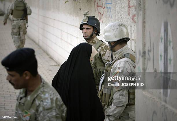 Iraqi soldiers stand guard as a woman heads to a polling centre after going through a security check in central Baghdad on March 7, 2010. Iraqis...