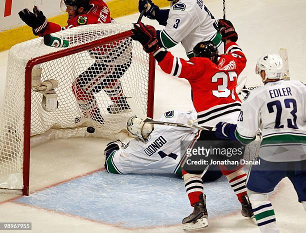 Roberto Luongo of the Vancouver Canucks reaches for the puck on a goal by Jonathan Toews of the Chicago Blackhawks while Adam Burish celebrates in...