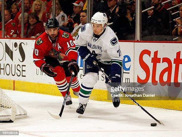 Mason Raymond of the Vancouver Canucks looks to pass under pressure from Patrick Sharp of the Chicago Blackhawks in Game Five of the Western...