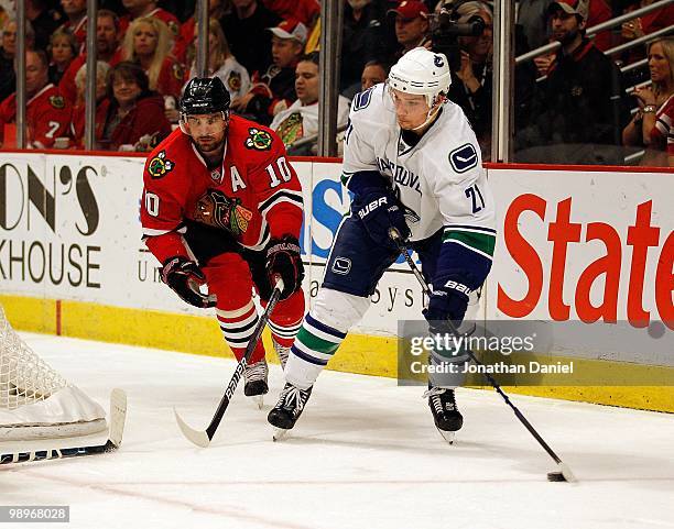 Mason Raymond of the Vancouver Canucks looks to pass under pressure from Patrick Sharp of the Chicago Blackhawks in Game Five of the Western...