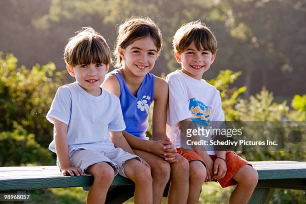 two boys and a girl sit for family portrait - newhealth stock pictures, royalty-free photos & images