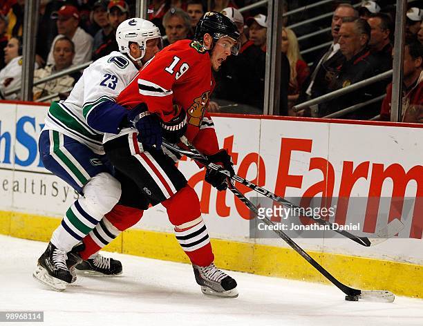 Jonathan Toews of the Chicago Blackhawks tries to control the puck under pressure from Alexander Edler of the Vancouver Canucks in Game Five of the...