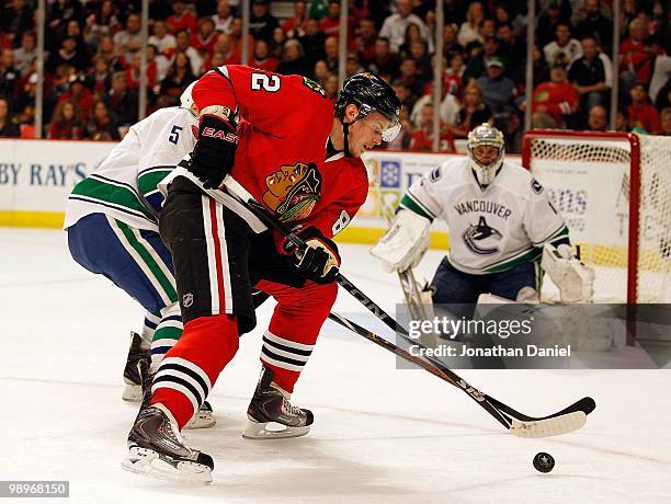 Tomas Kopecky of the Chicago Blackhawks controls the puck as Christian Ehrhoff of the Vancouver Canucks defends in front of teammate Roberto Luongo...