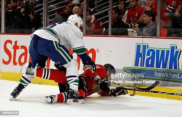 Tomas Kopecky of the Chicago Blackhawks is knocked down by Sami Salo of the Vancouver Canucks as he tries for the puck in Game Five of the Western...