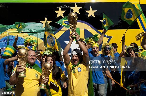 Holding copies of the World Cup trophy, Brazilian football fans await in front of a hotel in Rio de Janeiro, Brazil on May 11, 2010 the announcement...