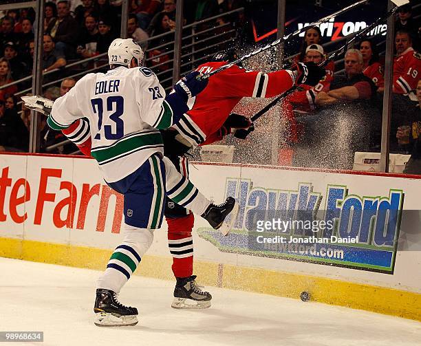 Dustin Byfuglien of the Chicago Blackhawks and Alexander Edler of the Vancouver Canucks kick up ice as they move to the puck in Game Five of the...