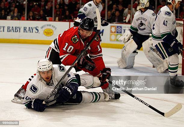 Michael Grabner of the Vancouver Canucks is knocked to the ice by Patrick Sharp of the Chicago Blackhawks in Game Five of the Western Conference...