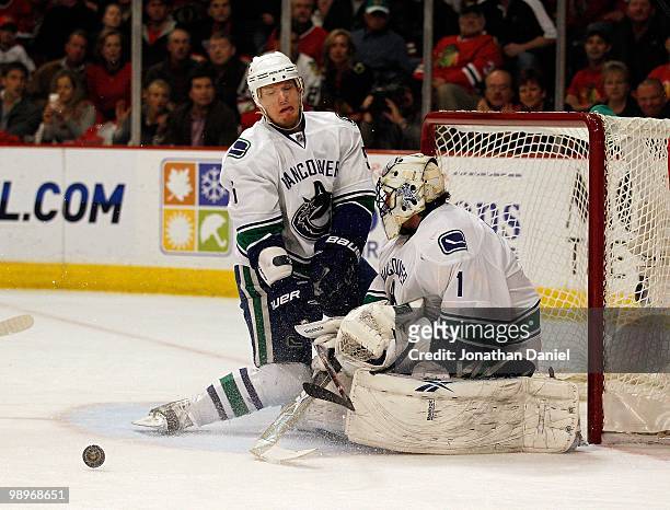 Christian Ehrhoff and Roberto Luongo of the Vancouver Canucks reject the puck against the Chicago Blackhawks in Game Five of the Western Conference...