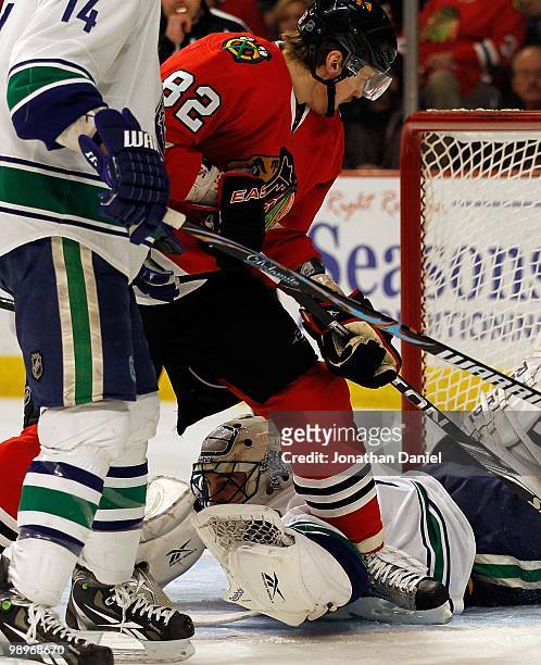 Roberto Luongo of the Vancouver Canucks dives under Tomas Kopecky of the Chicago Blackhawks to make a save in Game Five of the Western Conference...
