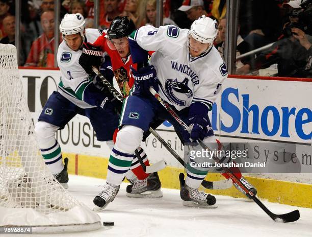 Jonathan Toews of the Chicago Blackhawks tries to slip between Kevin Bieksa and Christian Ehrhoff of the Vancouver Canucks as they move to the puck...