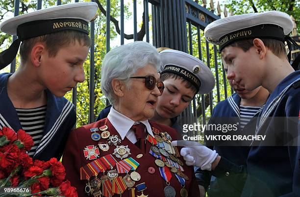 Russian navy cadets look at the medals of an elderly female WWII veteran near the Tomb of the Unknown Soldier in central Moscow on May 7, 2010....