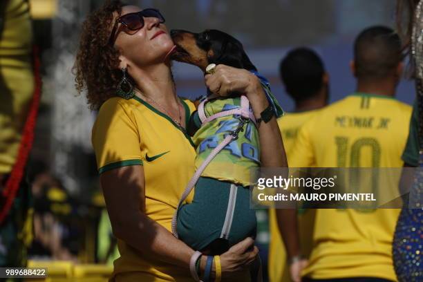 Fan of Brazil is licked by a dog as she waits to see the World Cup match between Brazil and Mexico on a big screen in Rio de Janeiro, Brazil, on July...