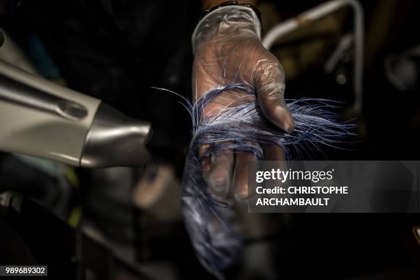 French feather worker Eric Charles-Donatien dries an ostrich feather after dyeing it at his studio in Paris, on June 20, 2018.