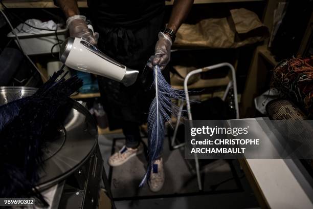 French feather worker Eric Charles-Donatien dries an ostrich feather after dyeing it at his studio in Paris, on June 20, 2018.