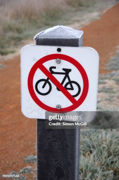 no bicycles sign on a post next to a dirt footpath at jerrabomberra wetlands, australian capital territory, australia - footpath sign stock pictures, royalty-free photos & images