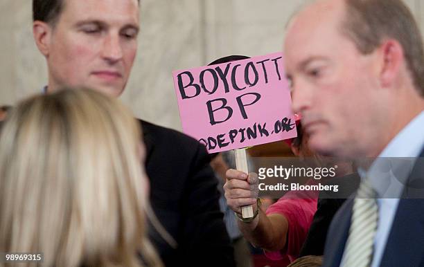 Protestor holds a sign behind Lamar McKay, president and chairman of BP America Inc., right, during a Senate Energy and Natural Resources Committee...