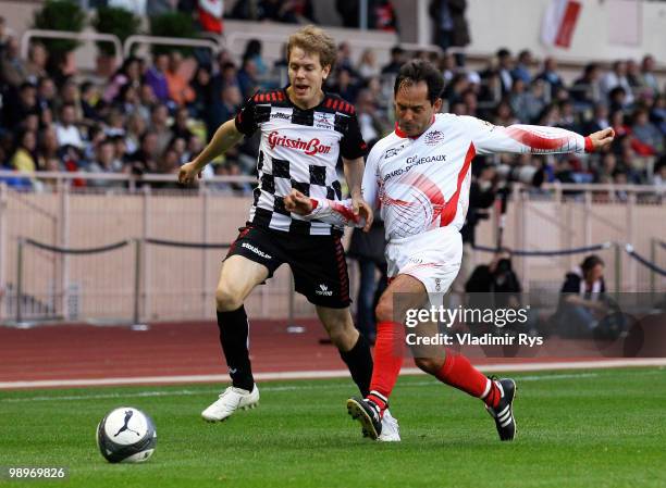 Sebastian Vettel of Germany and Red Bull Racing and Alex Caffi battle for the ball during the football charity match between the Monaco star team and...