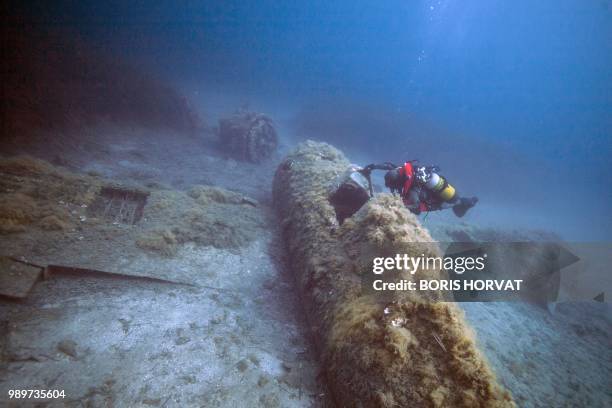 French military diver member of the FS Pluton M622 navy de-mining ship, swims on July 2 above the wreck of an USAAF P-47 Thunderbolt US fighter...