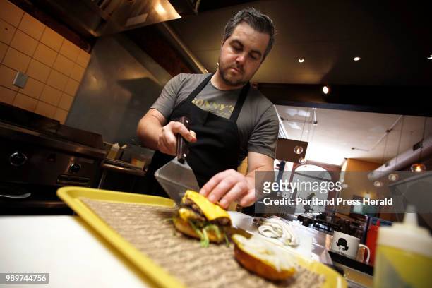 Nicholas Nappi, chef-owner of Black Cow on Exchange Street, slides a patty onto a grilled bun on Tuesday. Burger joints are a growing trend in...