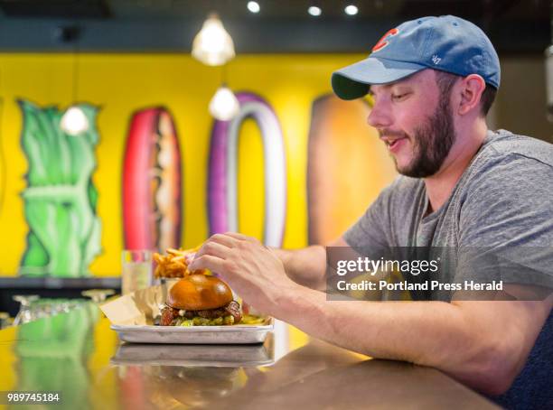 Garrett Jones of Portland reaches for a bacon burger, with bbq sauce, feta cheese at BRGR Bar on Brown Street in Portland Friday afternoon.