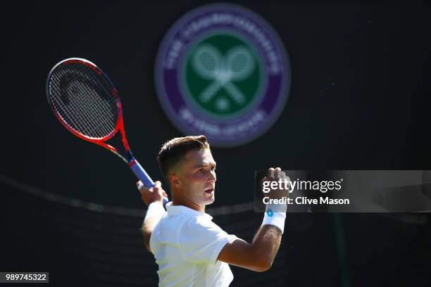 Liam Broady of Great Britain returns to Milos Raonic of Canada during their Men's Singles first round match on day one of the Wimbledon Lawn Tennis...