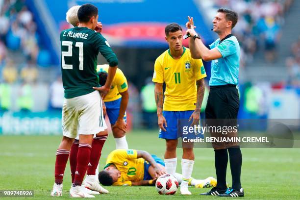 Italian referee Gianluca Rocchi gestures beside Brazil's forward Philippe Coutinho as Brazil's forward Neymar lies on the ground after being fouled...