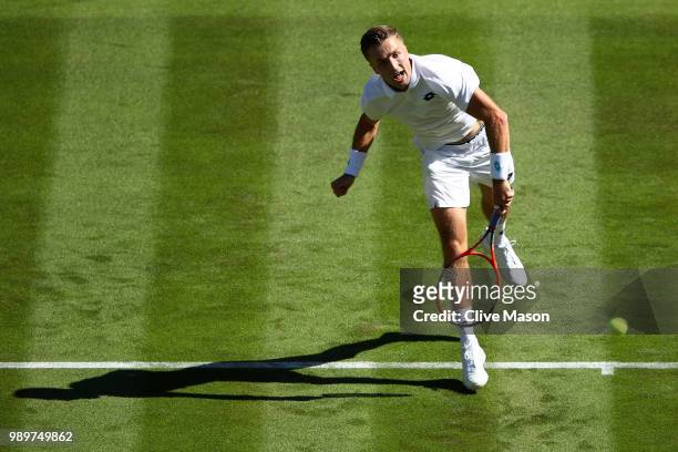 Liam Broady of Great Britain in action against Milos Raonic of Canada during their Men's Singles first round match on day one of the Wimbledon Lawn...