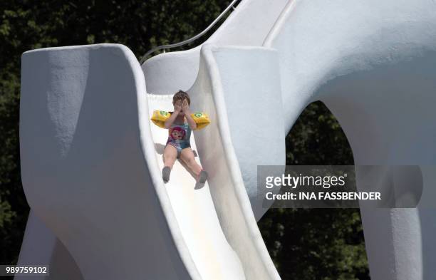 Girl holds her hands before her eyes as she slips down a water slide at the Grugabad public open air swimming pool in Essen, western Germany, where...