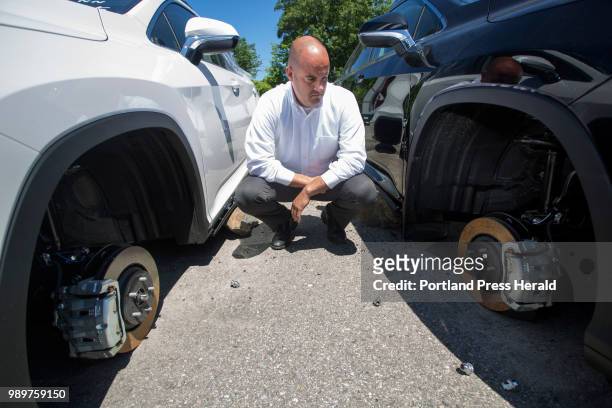 Matt Almy, general sales manager at Berlin City Auto Group in Portland, poses next to two Lexus RX 350 luxury SUVs with missing wheels on Tuesday,...
