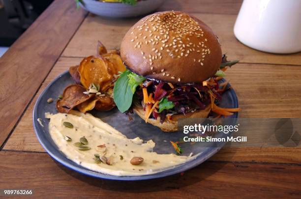 slow roasted beef burger with apple coleslaw and salad, served with hummous and sweet potato chips - sesame seed bun stock pictures, royalty-free photos & images