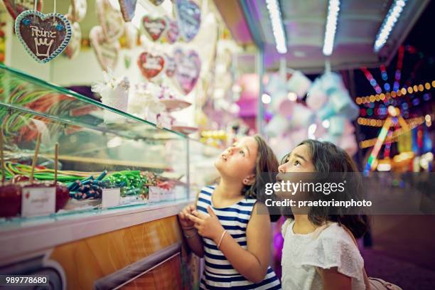 zwei kleine mädchen suchen süßigkeiten in den süßigkeiten-wagen auf der kirmes - cute girlfriends stock-fotos und bilder