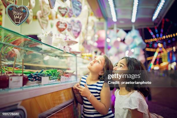 two little girls are looking sweets in the candy wagon at the fun fair - vienna holiday fair stock pictures, royalty-free photos & images