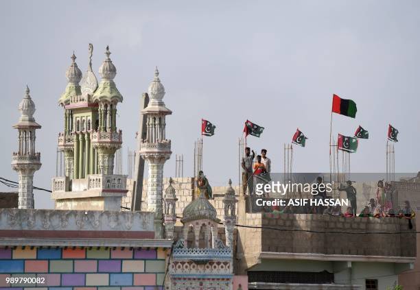 Supporters stand on a house rooftop as Chairman of the Pakistan Peoples Party Bilawal Bhutto Zardari arrives during an election campaign rally in...