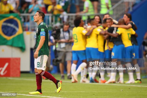 Andres Guardado of Mexico looks dejected as Roberto Firmino of Brazil celebrates after scoring a goal to make it 2-0 during the 2018 FIFA World Cup...