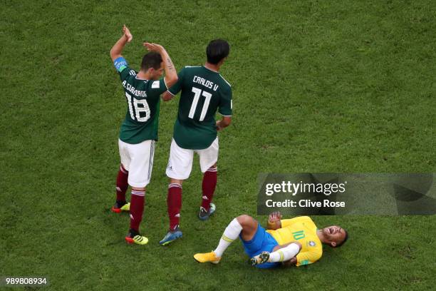 Neymar Jr of Brazil lies on the pitch injured while Andres Guardado and Carlos Vela of Mexico pass by during the 2018 FIFA World Cup Russia Round of...