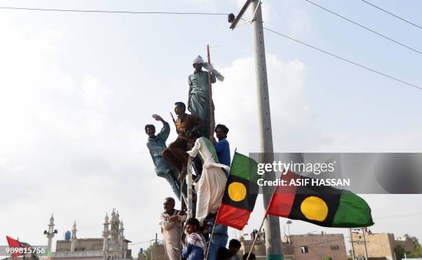 Supporters of Bilawal Bhutto Zardari, Chairman of Pakistan Peoples Party , climb on a pole during an election campaign rally in Thatta in southern...