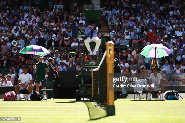 Grigor Dimitrov of Bulgaria and Stanislas Wawrinka of Switzerland during a break in their Men's Singles first round match on day one of the Wimbledon...