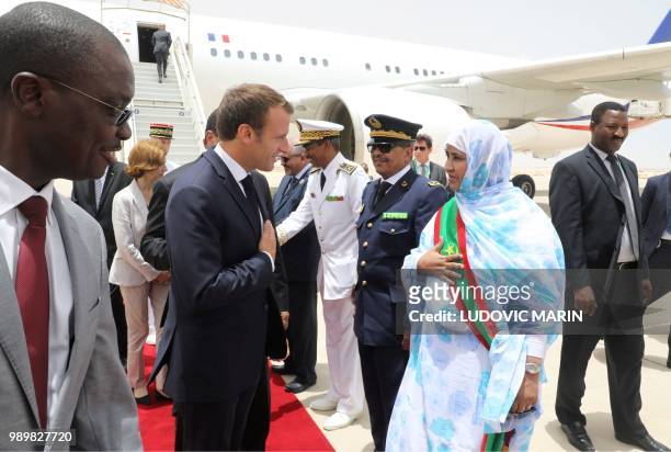 French President Emmanuel Macron is greeted by a Mauritanian female official upon his arrival at Nouakchott where he will attend the African Union...