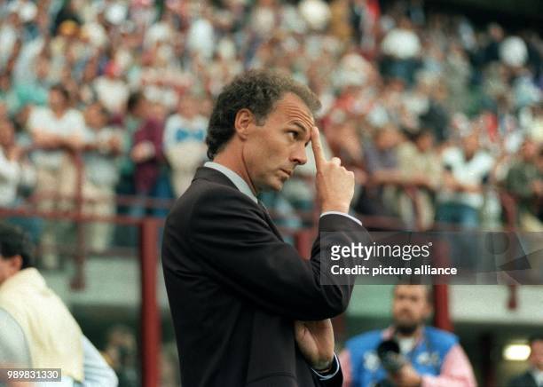 German head coach Franz Beckenbauer scratches his forehead as he observes the performance of his players on the pitch during the 1990 World Cup group...