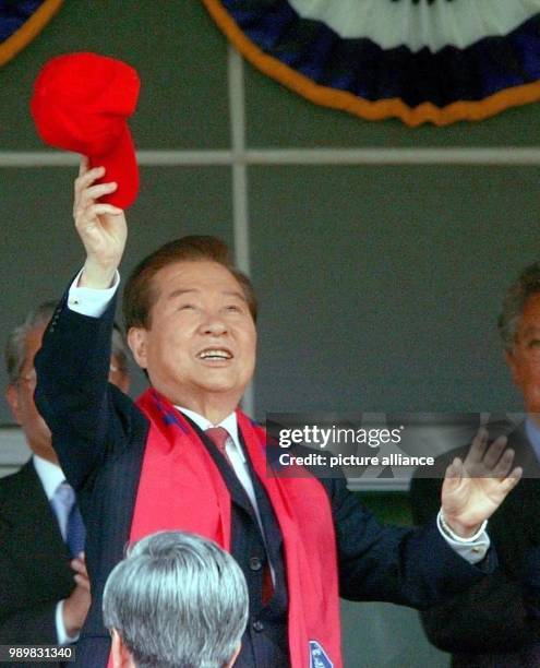 South Korean president Kim Dae Jung waves a fan cap to congratulate his team on the pitch duirng the World Cup quarter final South Korea against...