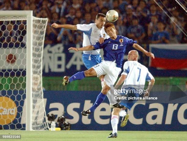 Japanese forward Atsushi Yanagisawa jumps up and manages a header in a struggle for the ball with Russians midfielder Andrej Solomatin and defender...