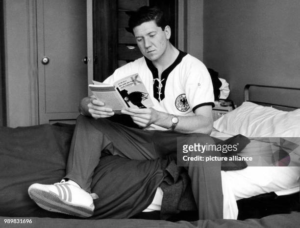 German midfielder Horst Szymaniak sits on his bed and reads a book at the accommodation of the German national soccer team during 1962 World Cup in...