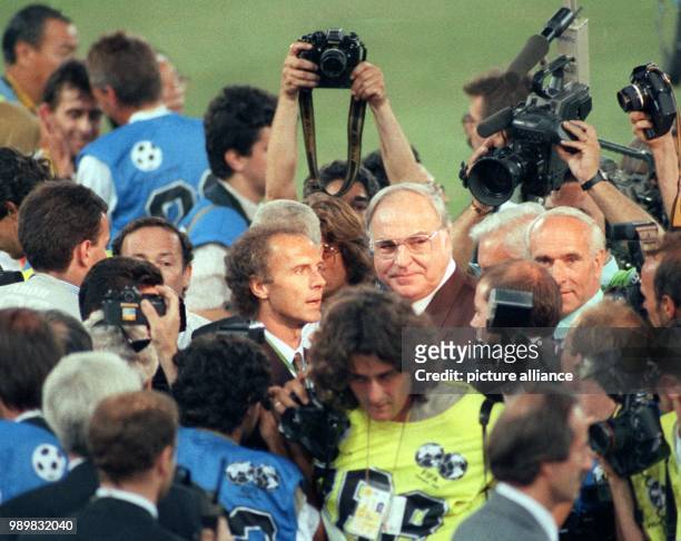 Former German chancellor Helmut Kohl and a content smiling Franz Beckenbauer, German head coach and team leader, stand surrounded by a dense crowd of...