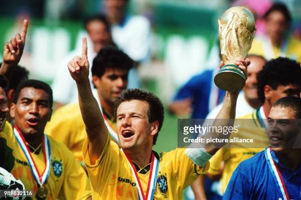 Brazilian team captain Dunga holds up the World Cup while he cheers and jubilates with his fellow teammates, among those midfielder Mauro Silva and...