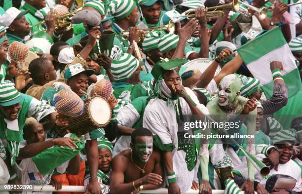 Nigerian fans wear clothes and painted faces with the national colours of Nigeria while they play on music instruments and cheer after Nigeria won...